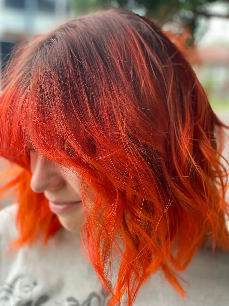 Textured shoulder-length cut in vivid copper orange with a fringe